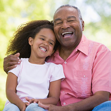 A grandfather and granddaughter laughing. Links to Gifts of Life Insurance
